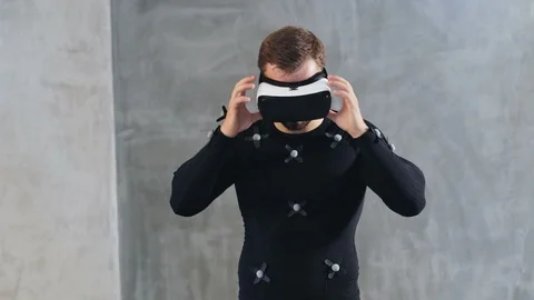 Front view of sport athletic man in VR glasses and mocap suit standing in front Stock Footage 93592480