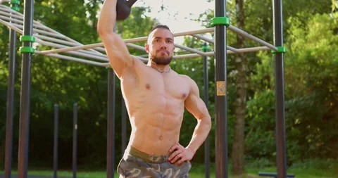 Front view of strong man doing Exercises at sports ground. Lifting kettlebell Stock Footage 157942925