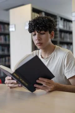 Front view of a student, deeply focused on his book. Foto stock