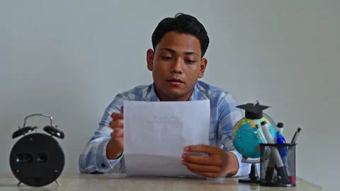 Front view of student reviewing scholarship application form with hopeful Stock Footage 334012510