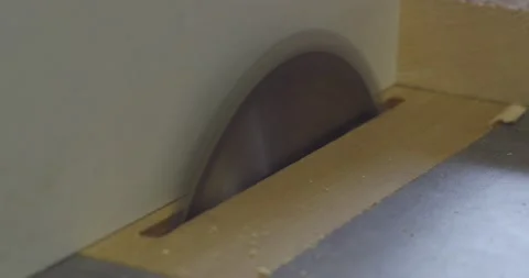 A front view of a table circular saw cutting a plywood board at a right angle. A Stock Footage 130463851