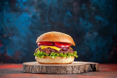 Front view tasty cheeseburger with meat tomatoes and green salad on dark bl.. Stock Photos
