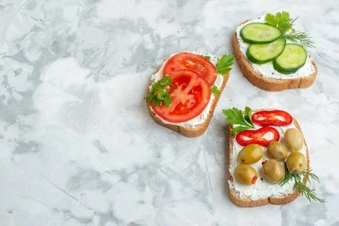 Front view tasty toasts with tomatoes olives peppers and cucumbers on white.. 写真素材