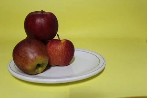 Front view three apples in plate on yellow background Stock Photos