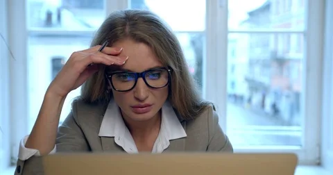 The front view of the tired and nervous blonde businesswoman working on the Stock Footage 84024371