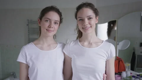 Front view two beautiful identical twins looking at each other turning to camera Stock Footage 165880171