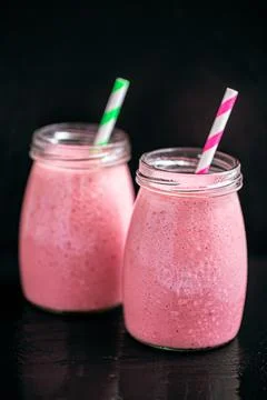 Front view of two berries milkshakes in glass jars on black background Stock Photos