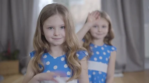 Front view of two Caucasian brunette twins waving at camera. Cute happy sisters Video stock 124674433