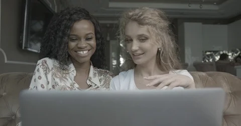 Front view of two charming smiling multicultural girlfriends using the laptop Stock Footage 84056236