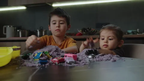 Front view of two creative kids making figures from kinetic sand at the kitchen Stock Footage 274130863