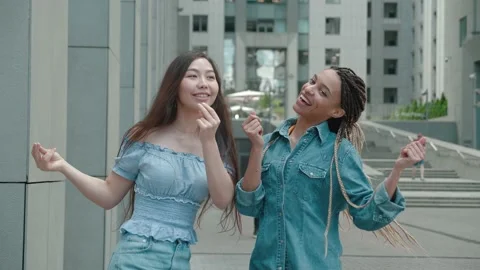 Front view Two cute funny asian and african american girls dancing on city Video stock 160036390