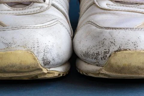 Front view of two old white sneakers with scuffed rubber soles, cracked material Stock Photos