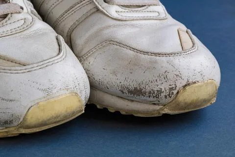 Front view of two old white sneakers with scuffed rubber soles, cracked material Fotos de archivo