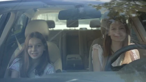 Front view of two pretty cheerful girls driving a car to their destination Stock Footage 112748995