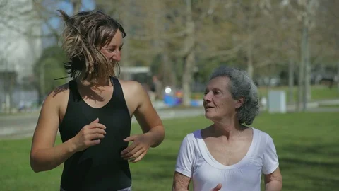 Front view of two women jogging in park, talking and smiling Stock Footage 105962267