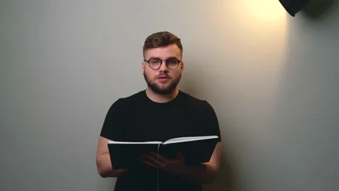 Front view video of a caucasian man reading a book in front of camera on a gray Stock Footage 150858201