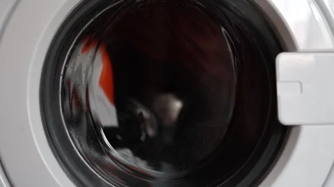Front view of a washing machine door with damp glass and blurred clothes inside  Video stock 312979318