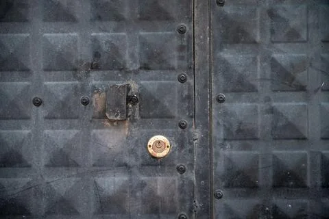Front view of weathered black iron door with keyhole and lock Stock Photos