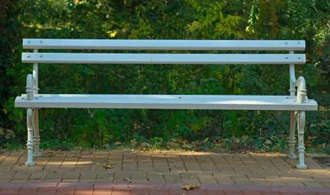 Front view on a white bench on red bricks with nature behind it Foto stock