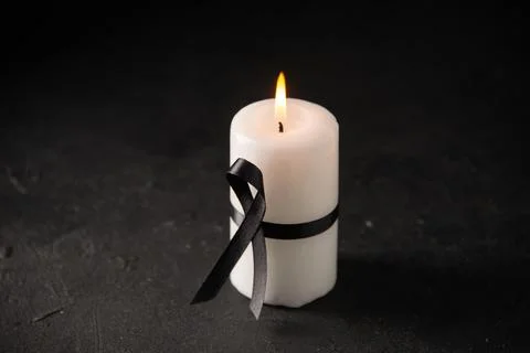 Front view of white candle with black bow on dark desk war funeral evil death Stock Photos