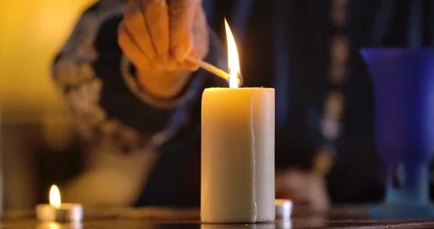 Front view of white candle standing on the table and female Caucasian hand Stock Footage 123149705