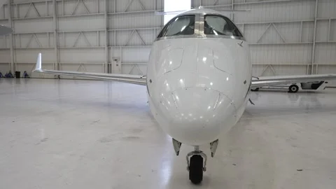 Front view of a white private airplane parked in a hangar. Stock Footage 278068753