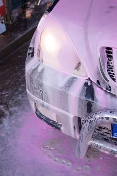 Front View of White SUV Covered in Bright Pink Active Cleaning Foam Stock Photos