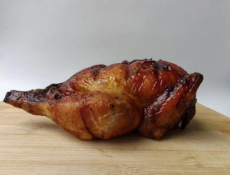 Front view of a whole roasted chicken on a wooden plank Stock Photos