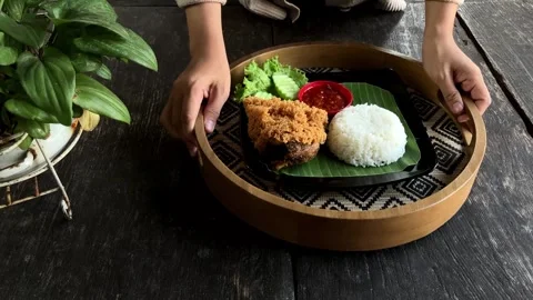 Front View of Woman Hand Serving Chicken Rice Plate on Patterned Wooden Tray 4K Stockbeeldmateriaal 337721040