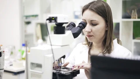 Front view of woman scientist using a microscope Stock Footage 75344178