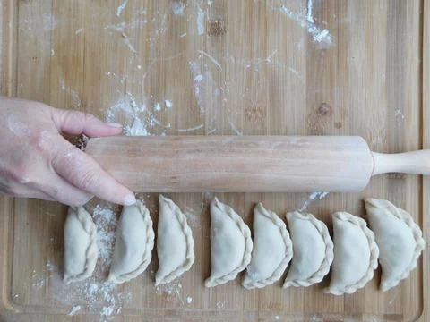 Front view of woman's hands making meat dumpling with wooden rolling pin. Foto stock