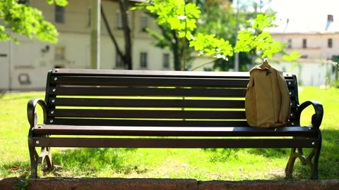 Front view of wooden empty bench with backpack on beautiful sunny background in 스톡 동영상 146793059