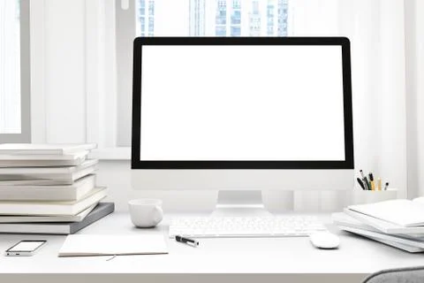 Front view of workpark with blank white computer screen, coffee cup, and book in Stock Photos