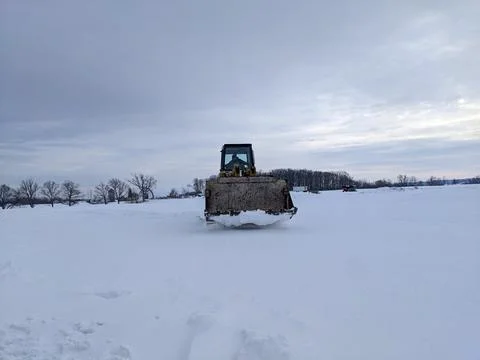 Front view of a yellow tracked loader driving through deep snow in a rural .. Stockfoto's