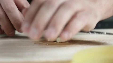 Front view of yong man cook cut thin slices of garlic with knife on cutting 库存影片 74346020