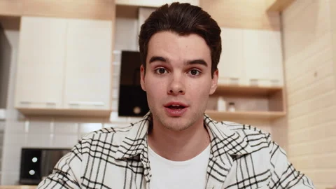 Front view of a young caucasian man in casual clothes sitting at home in a cozy Stock Footage 279564389