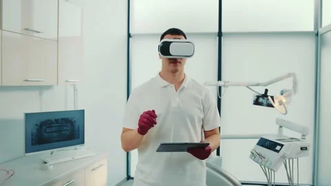 Front view of young dentist holding touchscreen, using virtual reality glasses Stock Footage 170828828