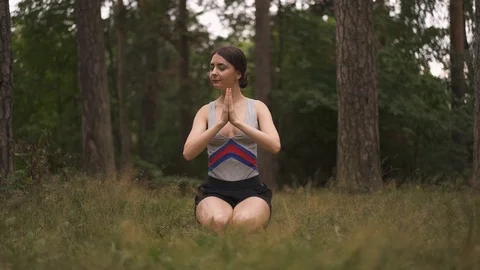 Front view of a young girl doing yoga in the forest Stock Footage 94971973
