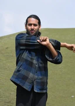 Front view of a young guy doing Cross Body Shoulder Stretch exercise in outdoor. Foto stock