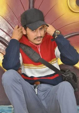 Front view of a young guy looking at camera while adjusting hoodie while sitting Stock Photos
