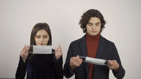 Front view of young man and woman putting on medical masks and looking at camera Stock Footage 124526436