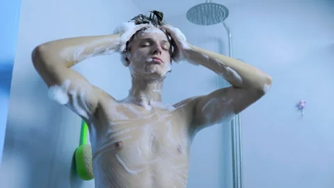Front view of a young man covered in foam taking a shower at home. Stock Footage 345531139