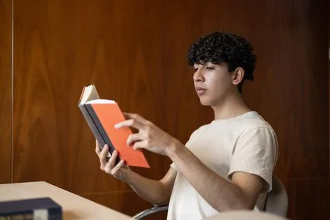 Front view of a young man, deeply engaged in a book. Foto stock