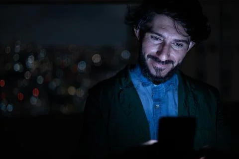 Front view of young man using a smartphone at night time with city view lands Stock Photos