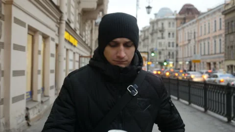 Front view of young man walking down the city street and drinking coffee.  Stock Footage 104833845