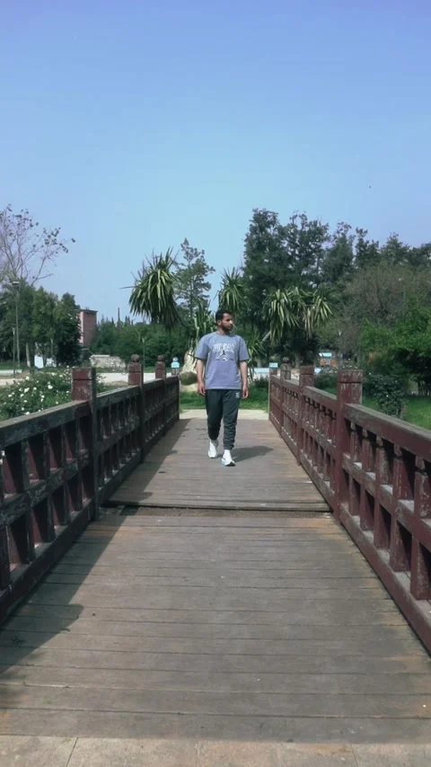Front View Young Man Walking On Wooden Bridge Park Morocco Stock Footage 339426675