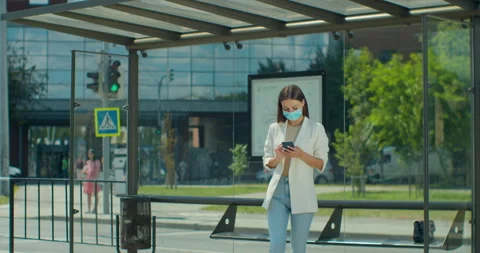 Front view of young woman using smartphone while waiting at public transport Stock Footage 137323651