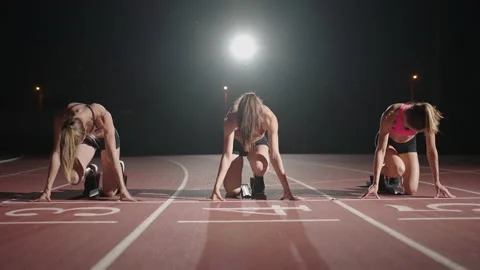 Front view zoom camera three women in the stadium at night in slow motion start Stock Footage 158854200