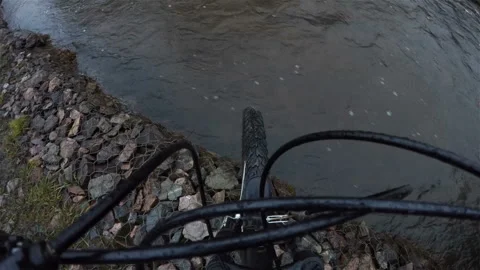 The front wheel of the Bicycle stands at the edge of the river Bank on the rocks Stock Footage 128155461