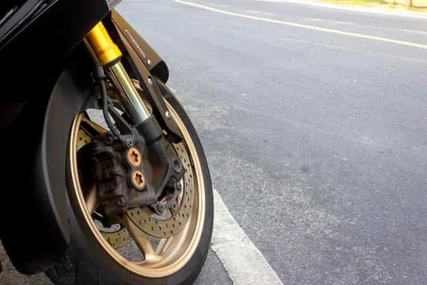 Front wheel caliper and abs disk brake of motorcycle stay on road Stock Photos